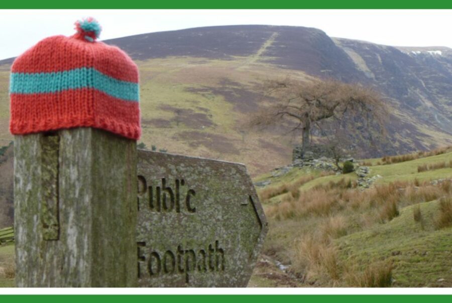 Extreme adventure: footpath sign in lake district with woolly hat on it
