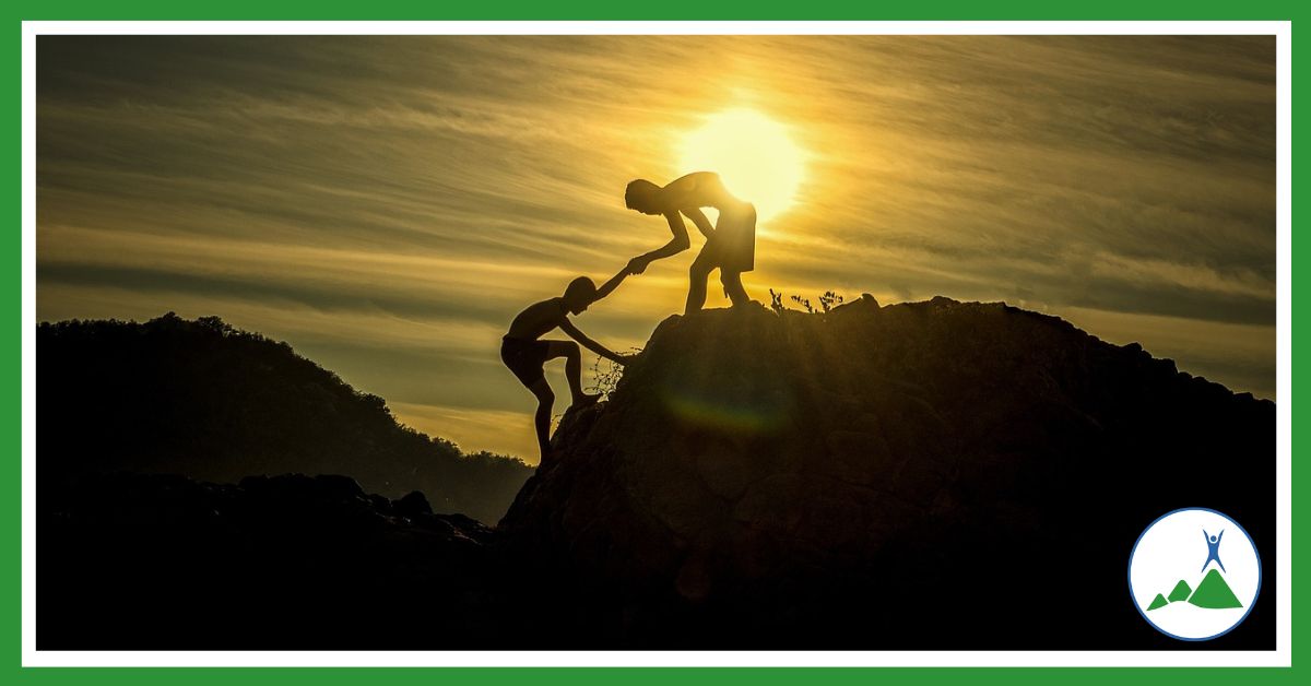 Friendship: one man helping another up a cliff